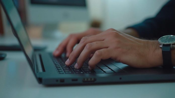 Gros plan des mains d'une personne tapant sur un clavier d'ordinateur portable